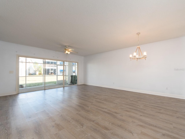 spare room featuring wood-type flooring and ceiling fan with notable chandelier