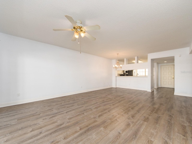 unfurnished living room featuring hardwood / wood-style floors, ceiling fan with notable chandelier, and a textured ceiling