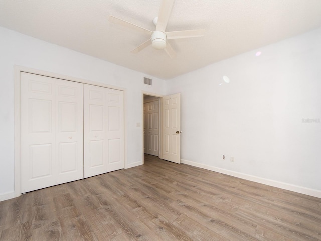 unfurnished bedroom with ceiling fan, light hardwood / wood-style flooring, and a closet