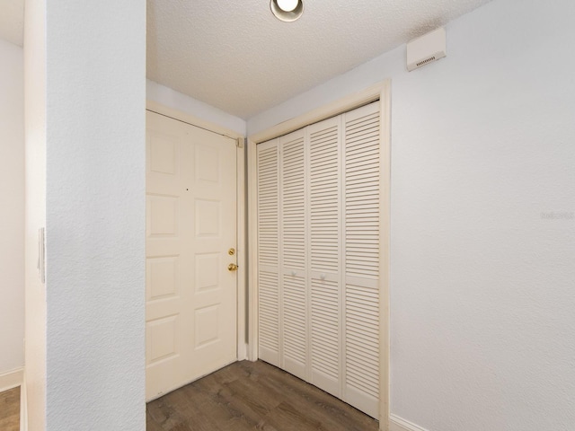 hall featuring a textured ceiling and dark hardwood / wood-style flooring