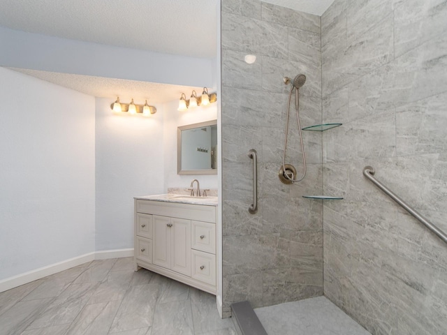 bathroom with a textured ceiling, vanity, and a tile shower