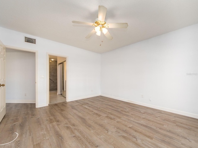 empty room featuring ceiling fan, light wood-type flooring, and a textured ceiling