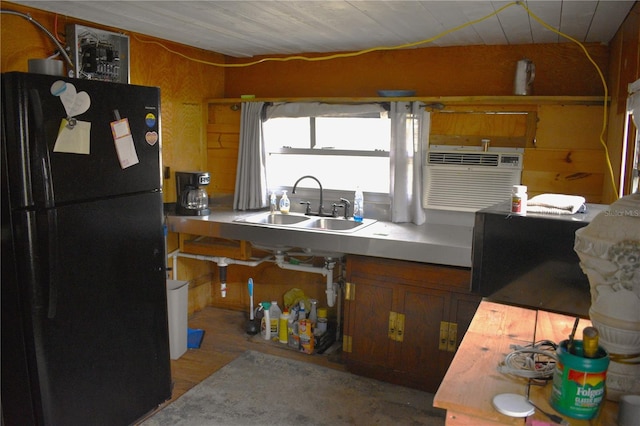 kitchen featuring black fridge, sink, and wooden walls