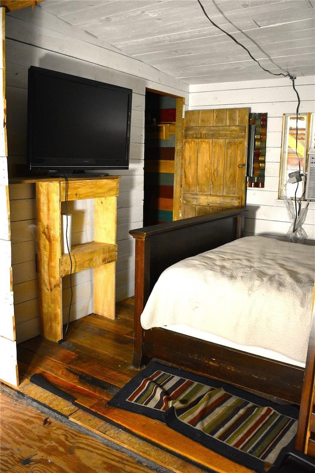 bedroom featuring dark hardwood / wood-style floors and wooden walls