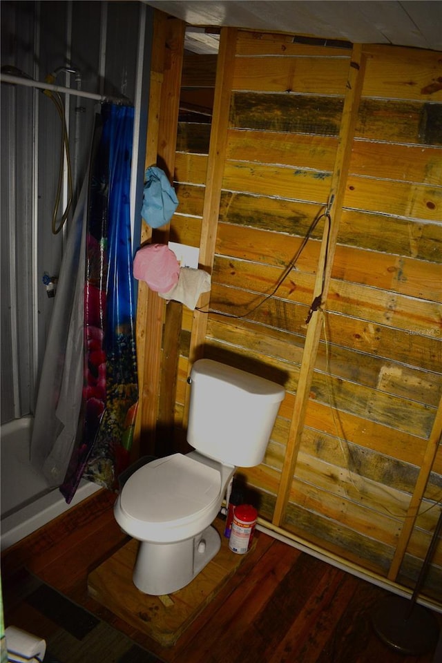 bathroom with wooden walls, toilet, and hardwood / wood-style flooring