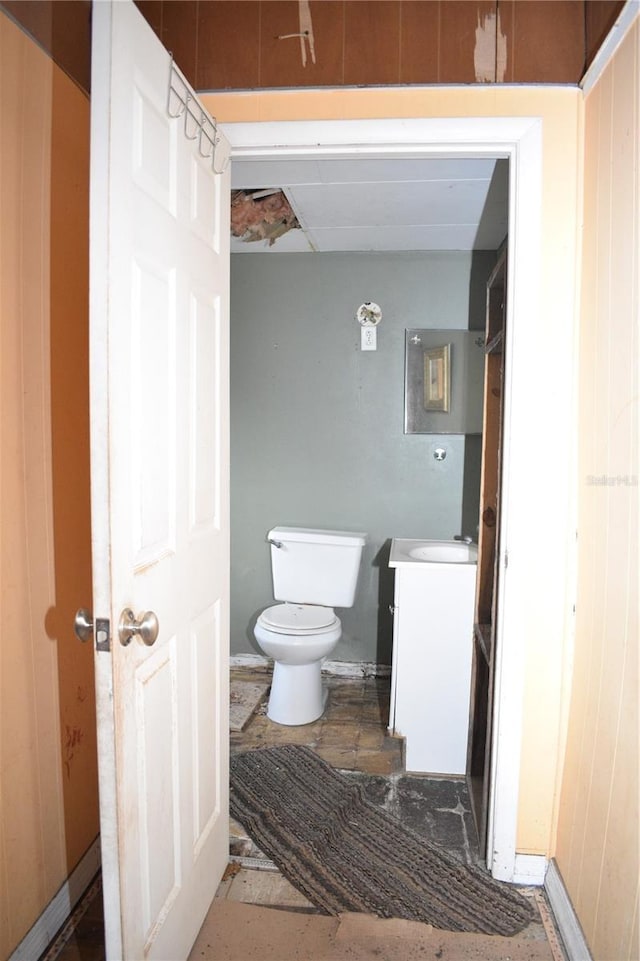 bathroom featuring wood walls, vanity, and toilet