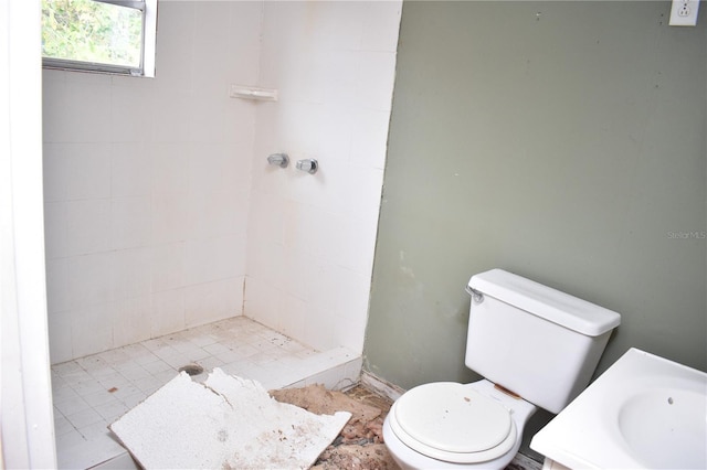 bathroom featuring a tile shower, vanity, and toilet