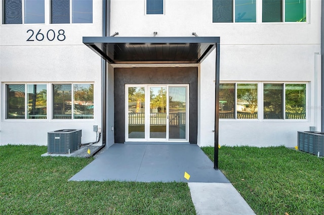 property entrance with central AC unit, a yard, and a patio