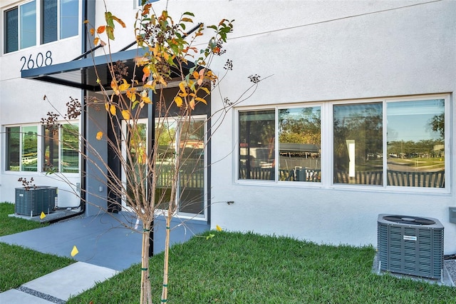 property entrance with a lawn and cooling unit