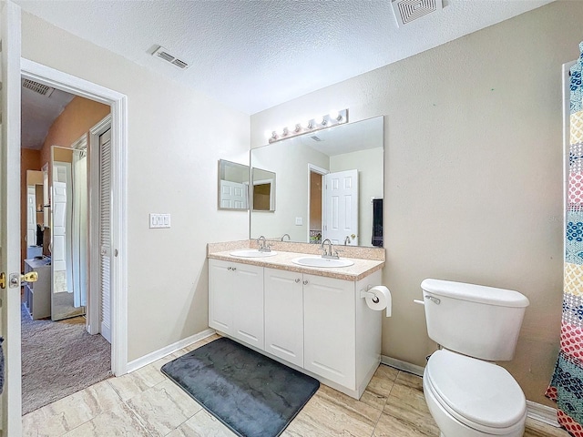 bathroom featuring vanity, toilet, and a textured ceiling