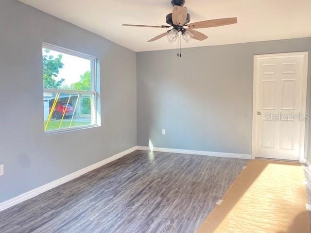 empty room with ceiling fan and dark hardwood / wood-style flooring