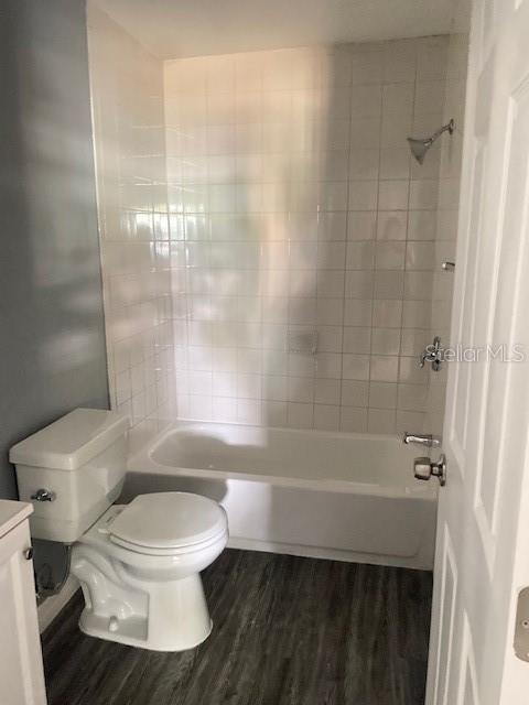 full bathroom featuring vanity, hardwood / wood-style flooring, toilet, and tiled shower / bath combo