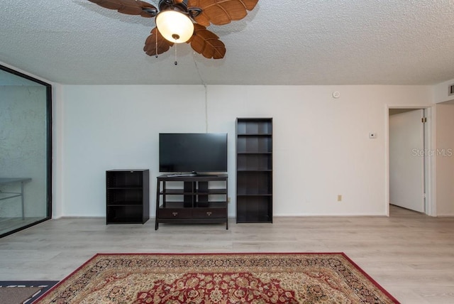 living room with ceiling fan, a textured ceiling, and light hardwood / wood-style flooring