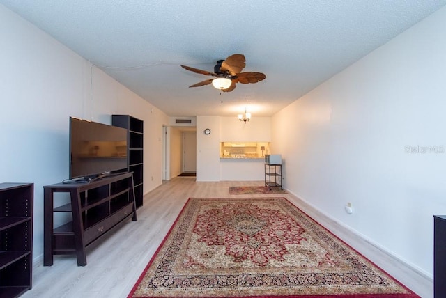 living room featuring ceiling fan, a textured ceiling, and light wood-type flooring