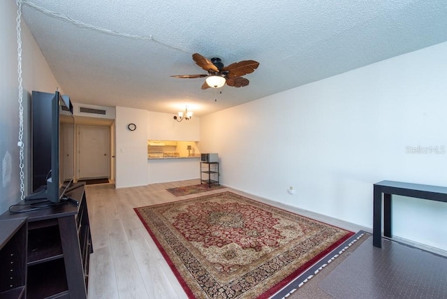 living room with hardwood / wood-style floors, ceiling fan with notable chandelier, and a textured ceiling