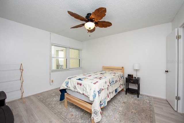 bedroom featuring a textured ceiling, light hardwood / wood-style floors, and ceiling fan