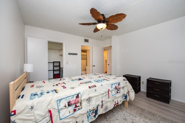 bedroom featuring ceiling fan, wood-type flooring, a textured ceiling, and connected bathroom