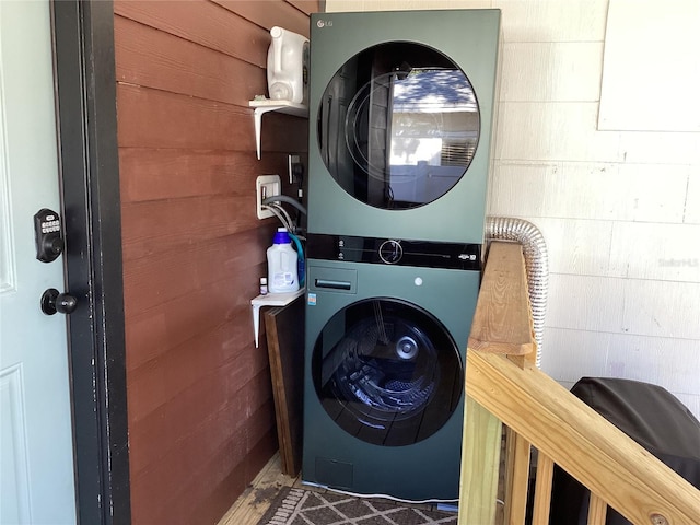 washroom with wooden walls and stacked washer and clothes dryer