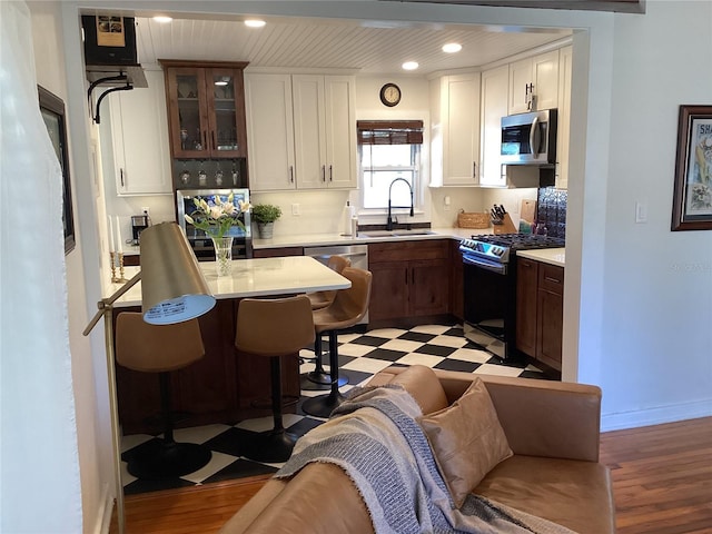 1529 Paloma Ln, Dunedin, FL 34698 - kitchen featuring a sink, appliances with stainless steel finishes, light countertops, a breakfast bar area, and glass insert cabinets