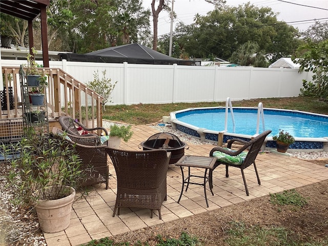 1529 Paloma Ln, Dunedin, FL 34698 - view of swimming pool featuring an outdoor fire pit, a fenced backyard, a wooden deck, and a patio