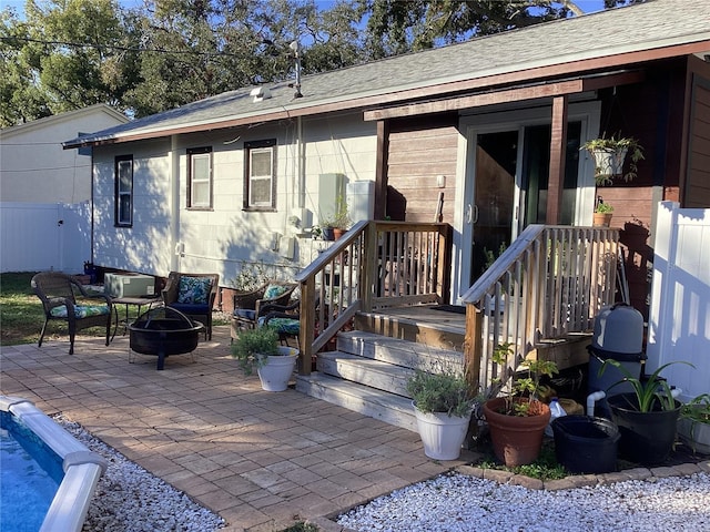 1529 Paloma Ln, Dunedin, FL 34698 - rear view of house with an outdoor fire pit, a patio area, fence, and a shingled roof