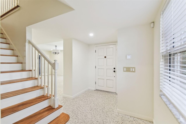 entryway with an inviting chandelier, baseboards, stairway, and light speckled floor