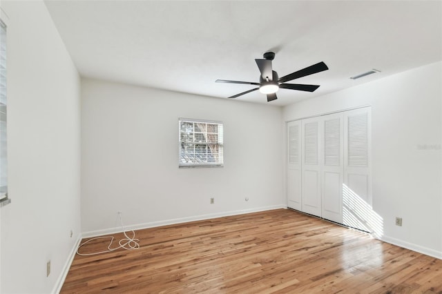 unfurnished bedroom featuring ceiling fan, light wood-style flooring, visible vents, baseboards, and a closet