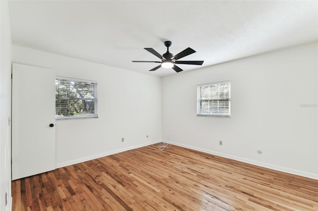 unfurnished room featuring a ceiling fan, wood finished floors, a wealth of natural light, and baseboards