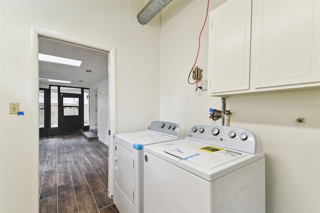 clothes washing area featuring wood finish floors, cabinet space, and washer and clothes dryer