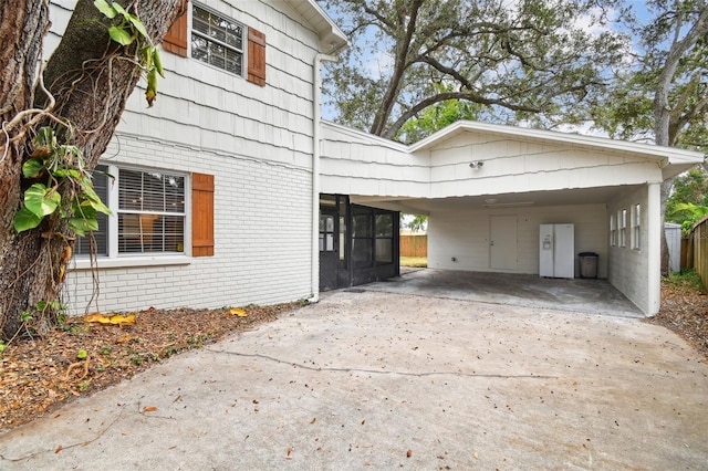 view of side of property featuring driveway, a carport, and brick siding