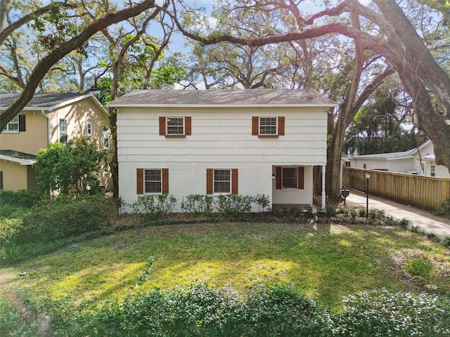 view of front of house featuring a front yard, brick siding, and fence