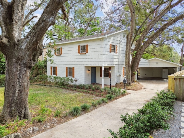 view of front of house featuring a carport, driveway, brick siding, and a front lawn