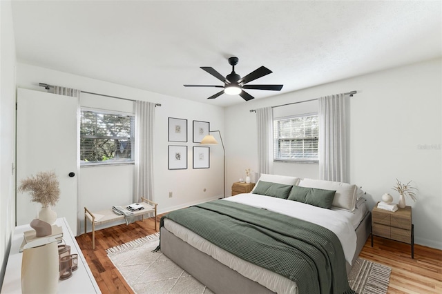 bedroom with baseboards, light wood-style flooring, and a ceiling fan