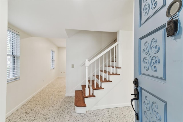 entrance foyer with stairway, baseboards, and light speckled floor