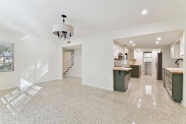 kitchen featuring decorative light fixtures, freestanding refrigerator, white cabinets, and wood counters