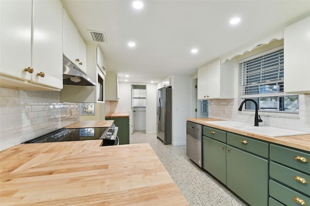 kitchen with white cabinets, green cabinets, stainless steel appliances, under cabinet range hood, and wooden counters