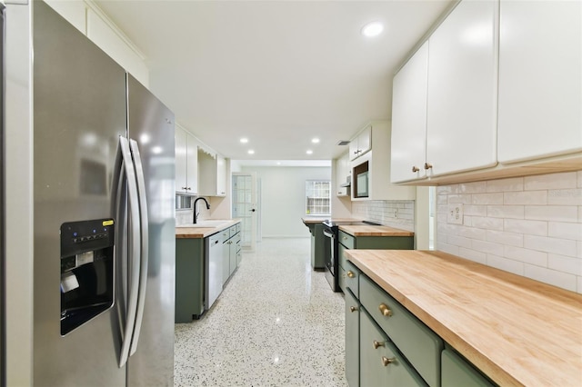 kitchen with electric range oven, stainless steel refrigerator with ice dispenser, a sink, and white cabinets