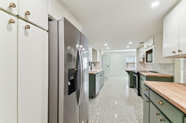 kitchen featuring appliances with stainless steel finishes, white cabinets, a sink, and wood counters