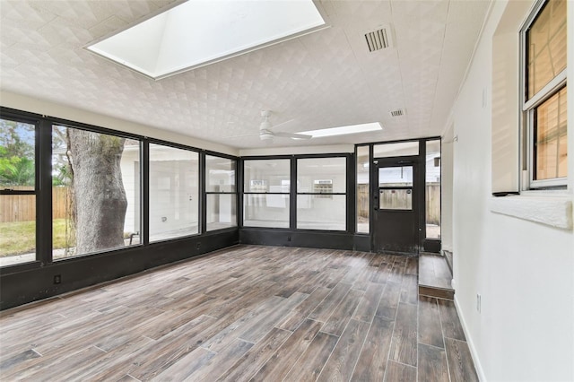 unfurnished sunroom featuring ceiling fan, a skylight, and visible vents