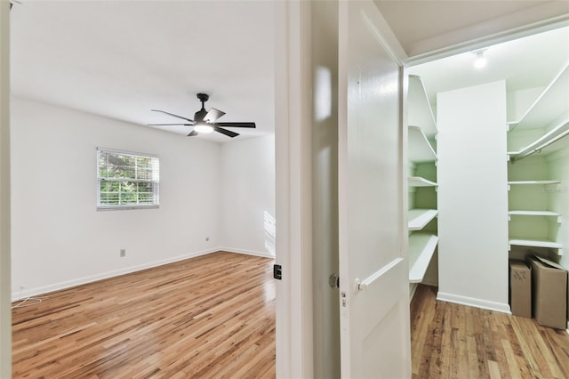 interior space featuring light wood finished floors, baseboards, and a ceiling fan