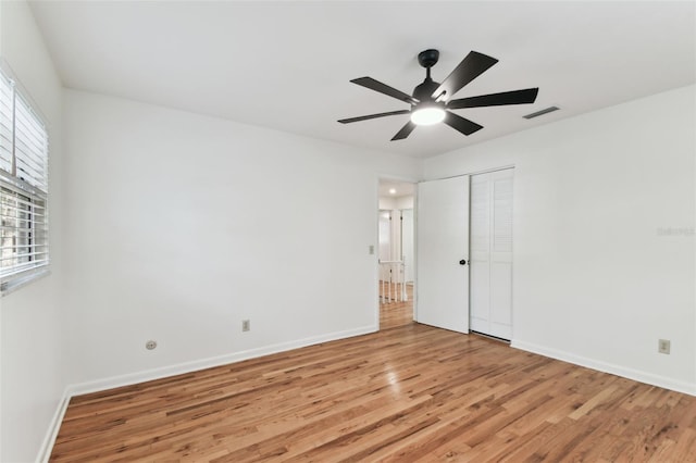 unfurnished bedroom with ceiling fan, light wood-style flooring, visible vents, baseboards, and a closet