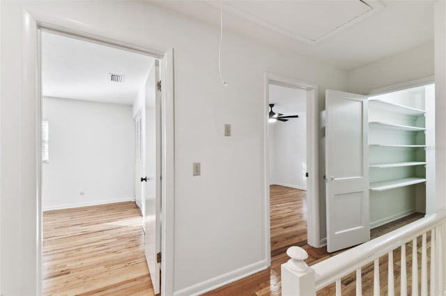 hall featuring attic access, baseboards, and wood finished floors