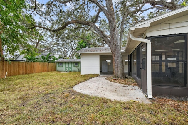 view of yard with an outbuilding, fence, and a sunroom