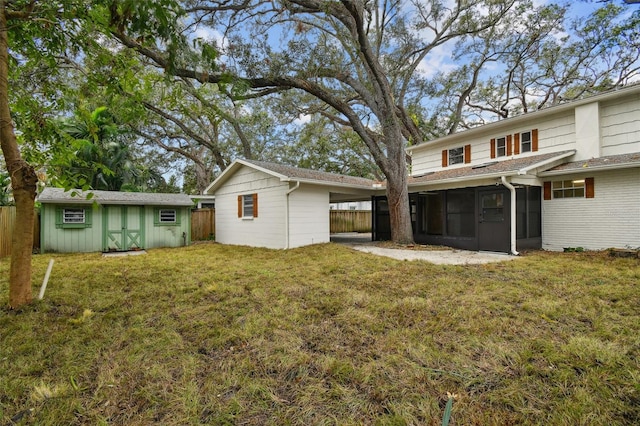 rear view of property featuring a lawn, an outdoor structure, fence, and a sunroom