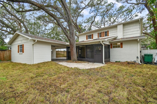 rear view of house featuring a sunroom, fence, brick siding, and a yard