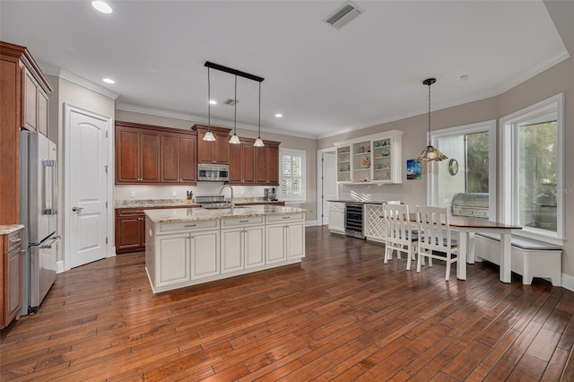 kitchen featuring stainless steel appliances, a kitchen island with sink, dark wood-type flooring, and decorative light fixtures