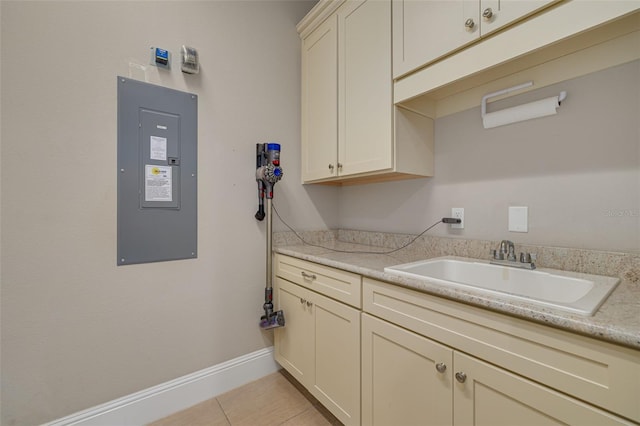 laundry area with electric panel, sink, and light tile patterned floors