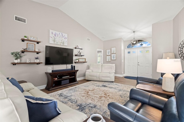 living room with a notable chandelier, vaulted ceiling, and dark hardwood / wood-style flooring