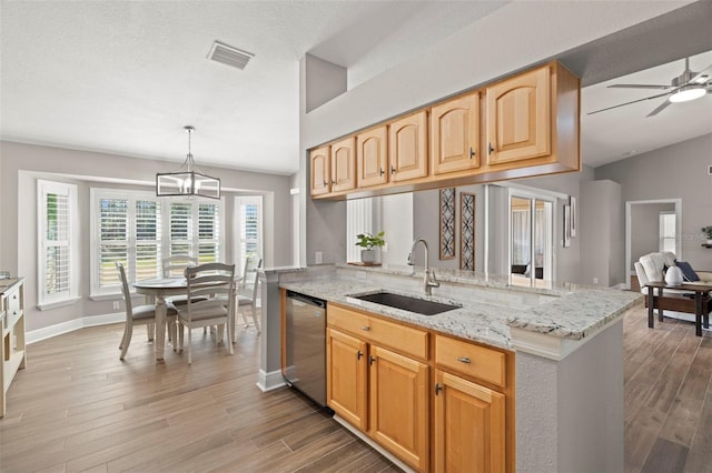 kitchen with stainless steel dishwasher, sink, decorative light fixtures, light stone countertops, and hardwood / wood-style floors