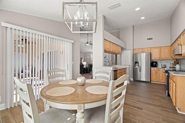 dining room with ceiling fan with notable chandelier, sink, dark hardwood / wood-style flooring, and lofted ceiling